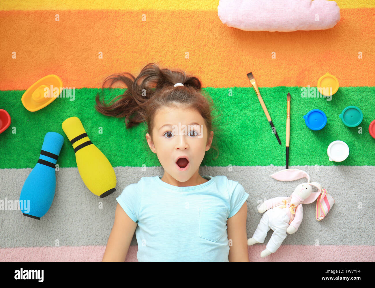 Cute little girl with toys on color carpet in kindergarten Stock Photo ...