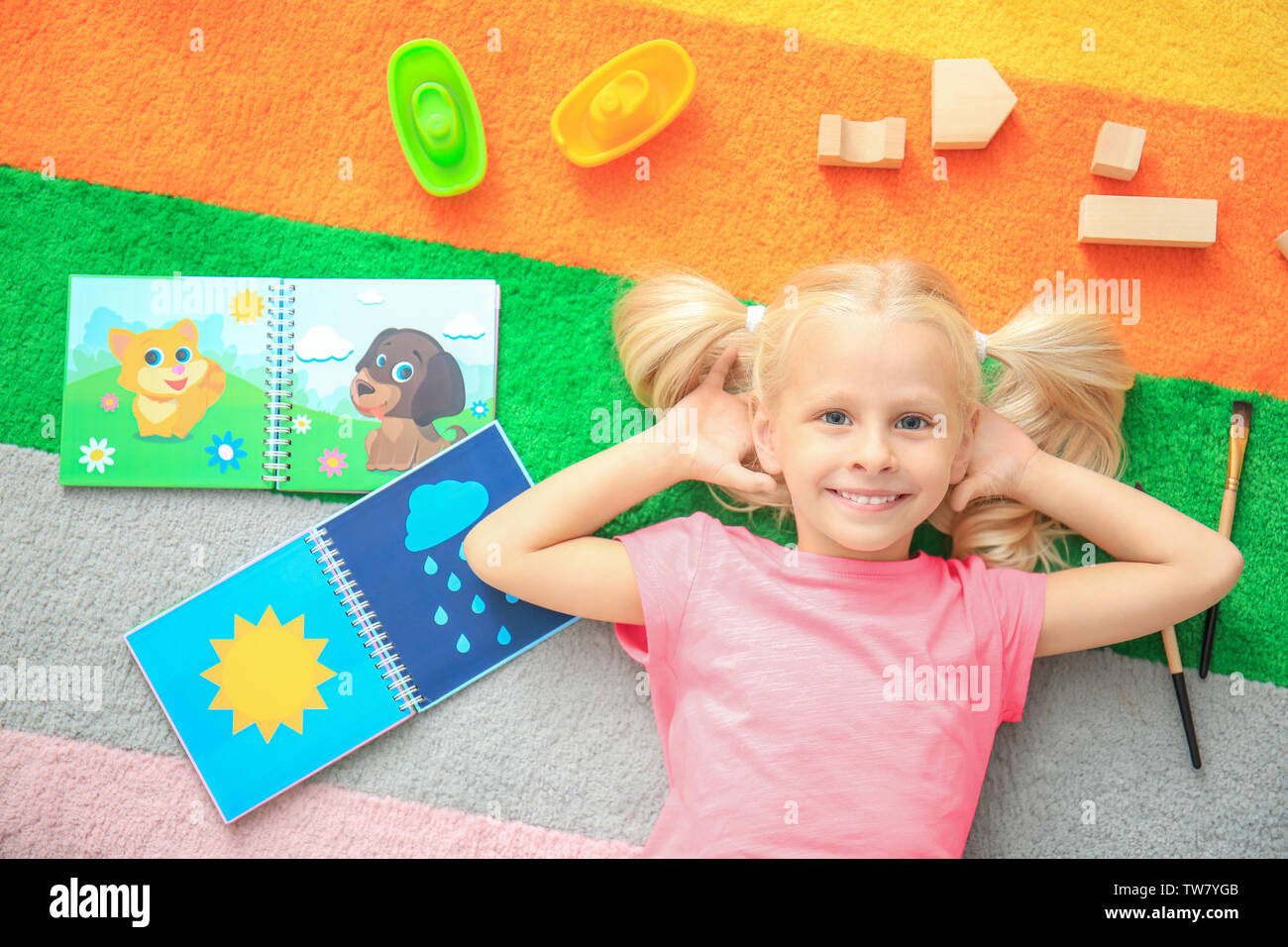 Cute little girl with toys on color carpet in kindergarten Stock Photo ...