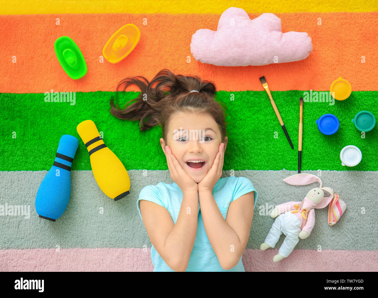 Cute little girl with toys on color carpet in kindergarten Stock Photo ...