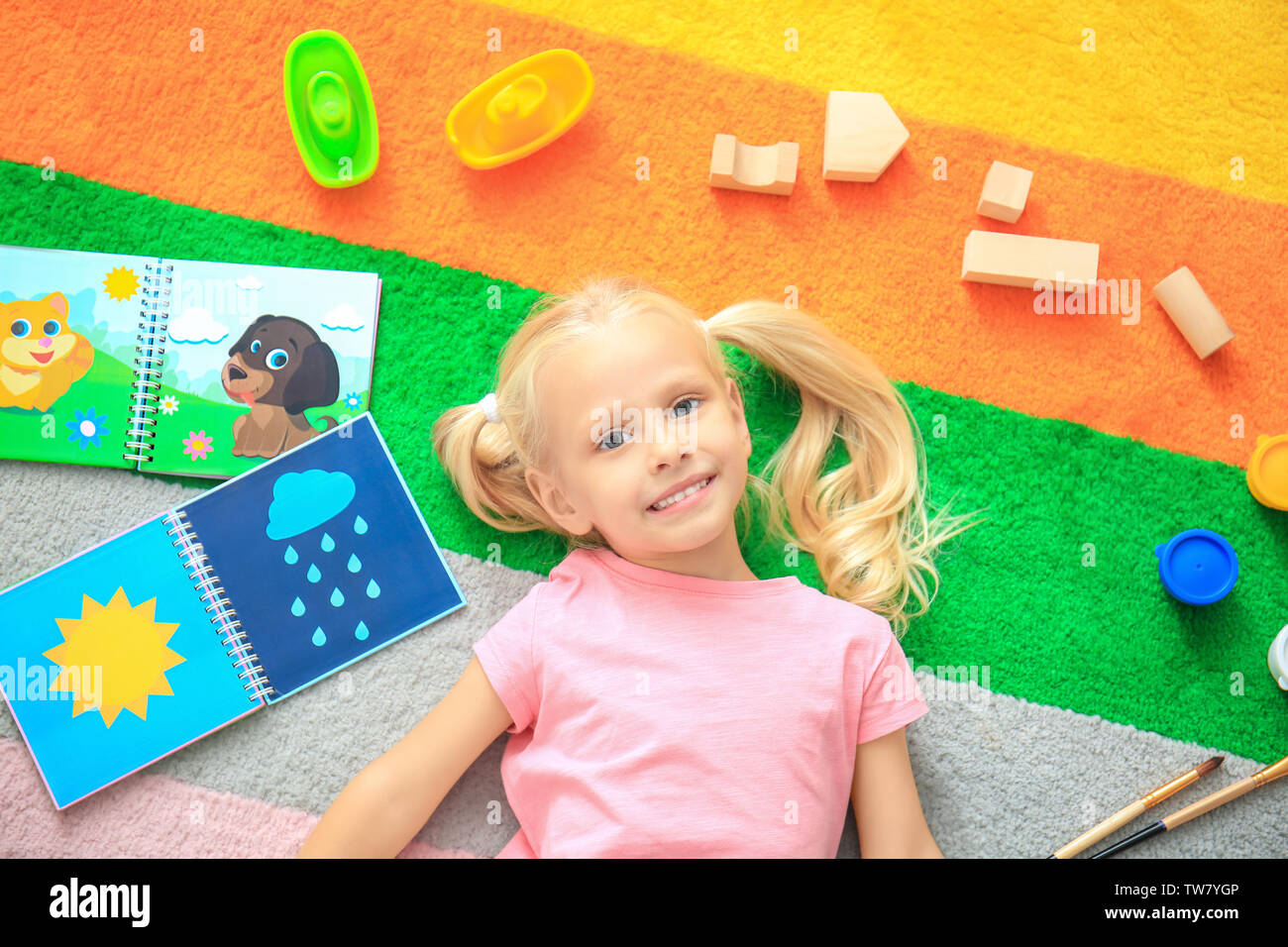 Cute little girl with toys on color carpet in kindergarten Stock Photo ...