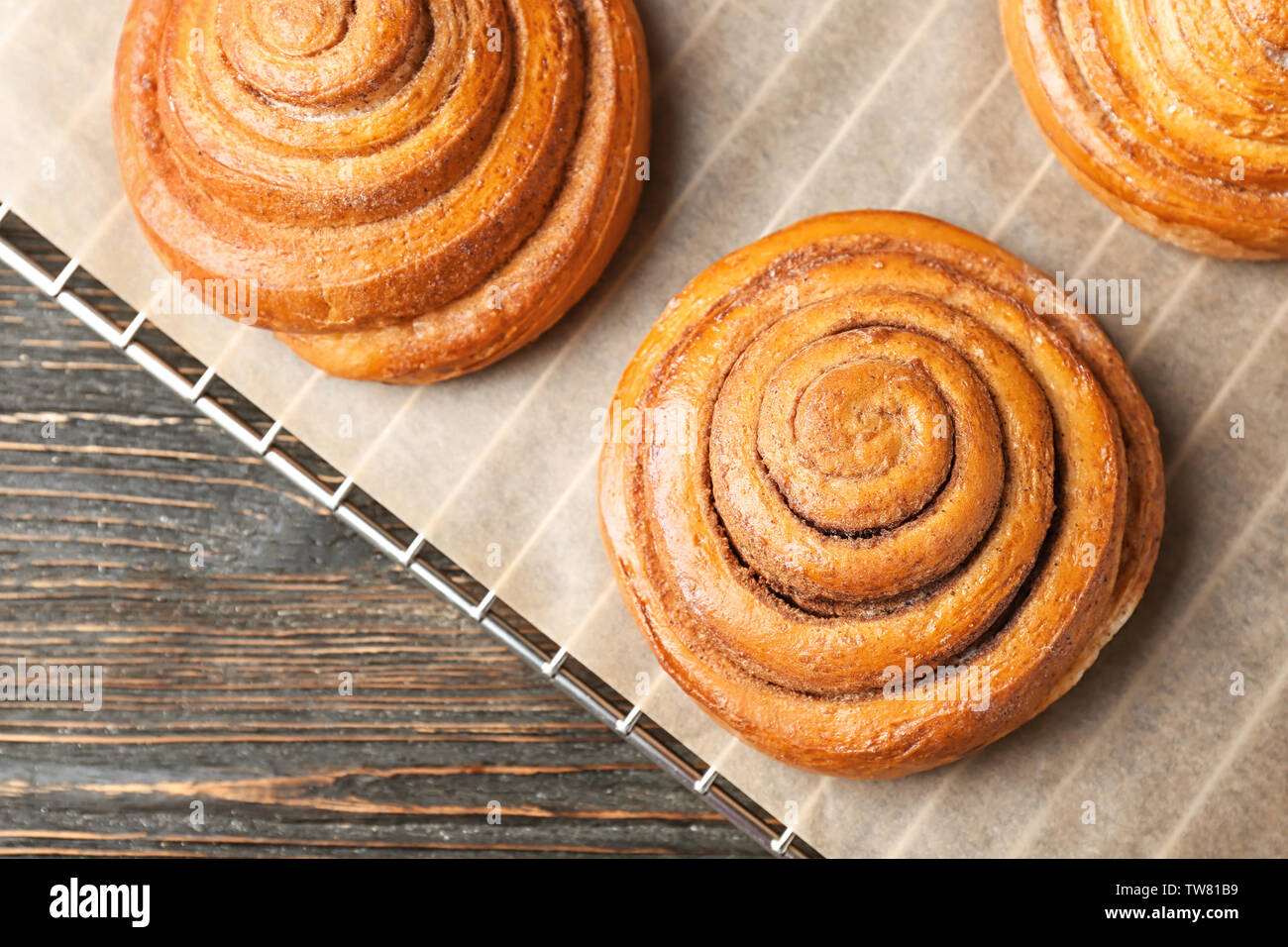 Cooling rack with sweet cinnamon rolls on table Stock Photo