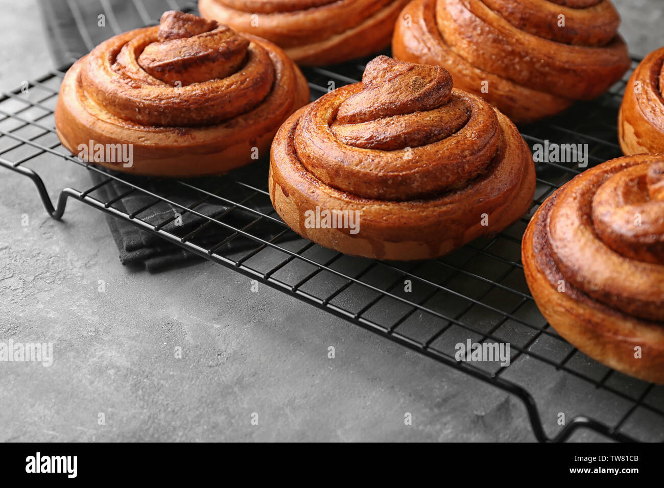 Cooling rack with sweet cinnamon rolls on table Stock Photo