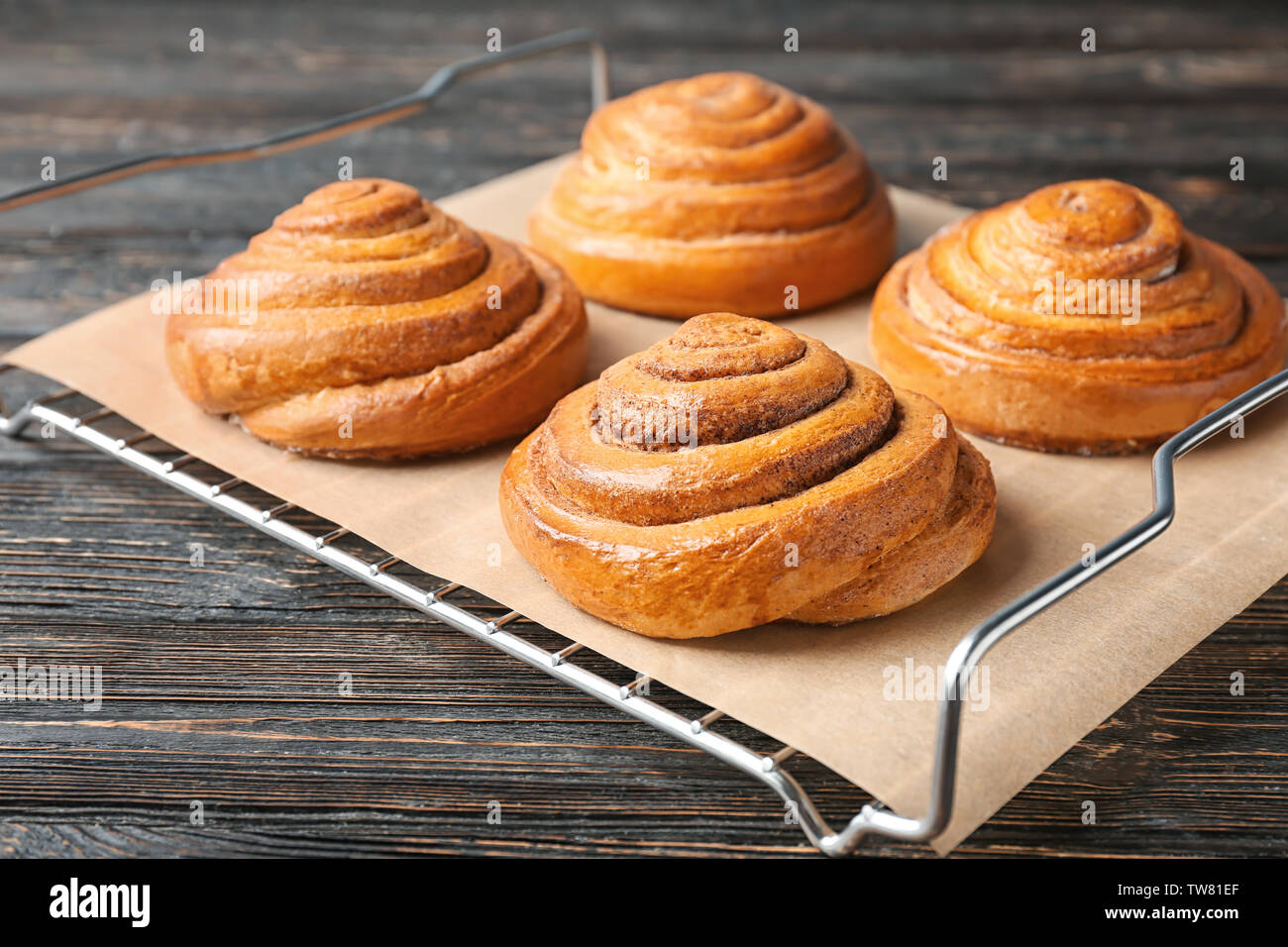 Cooling rack with sweet cinnamon rolls on table Stock Photo