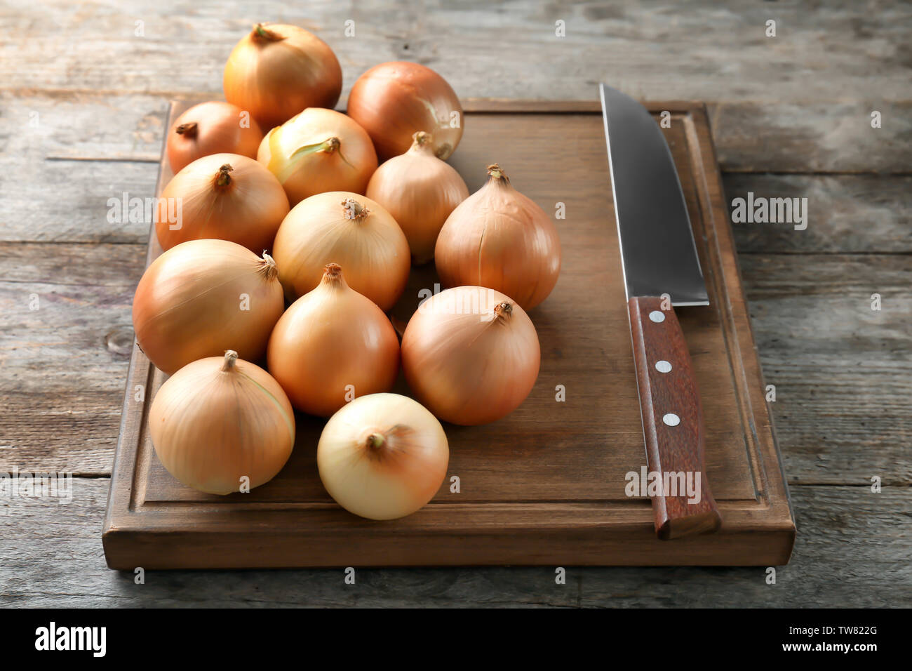Board with fresh raw yellow onion and knife on wooden background Stock ...