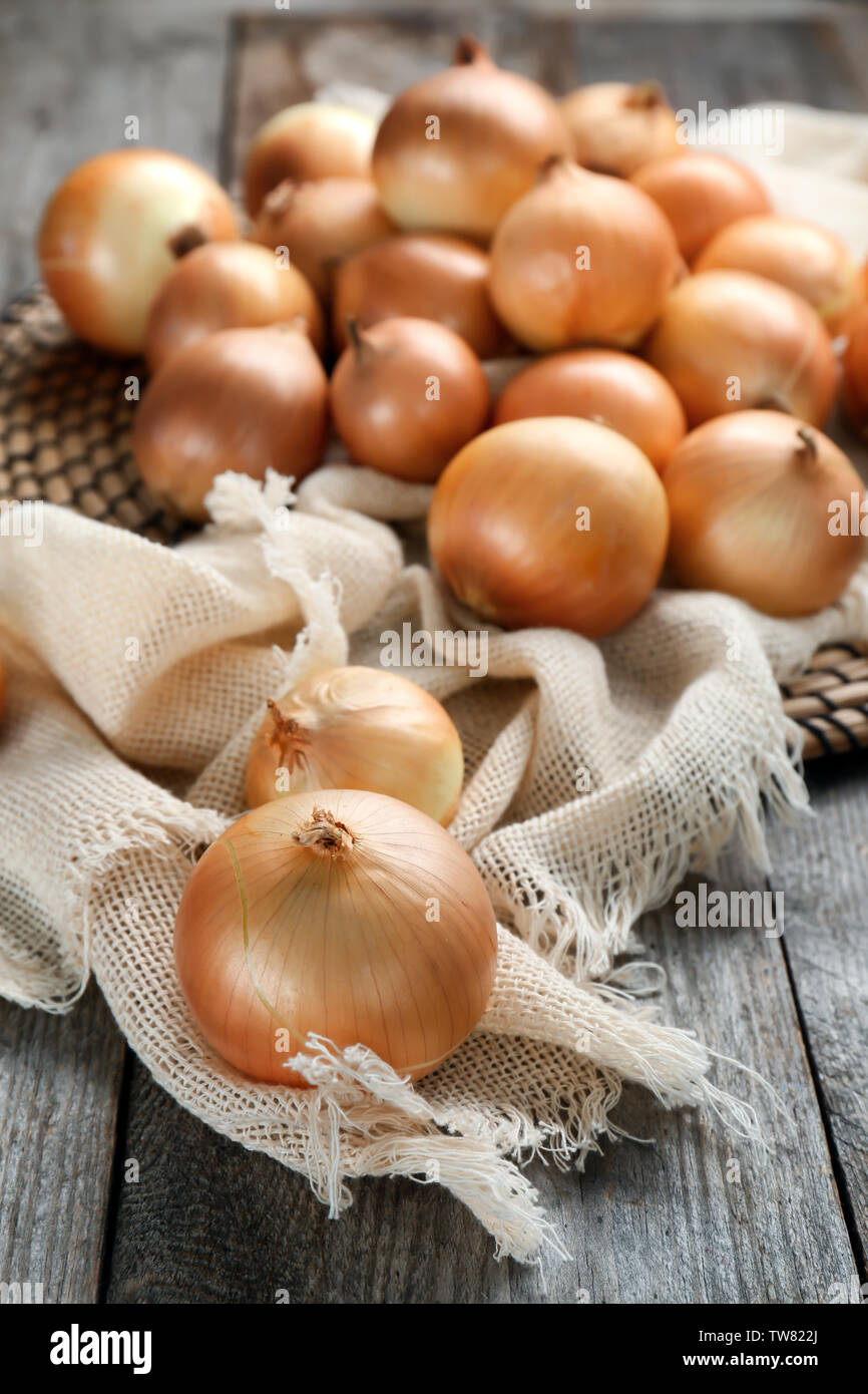 Wicker mat and fabric with fresh raw yellow onion on wooden background ...