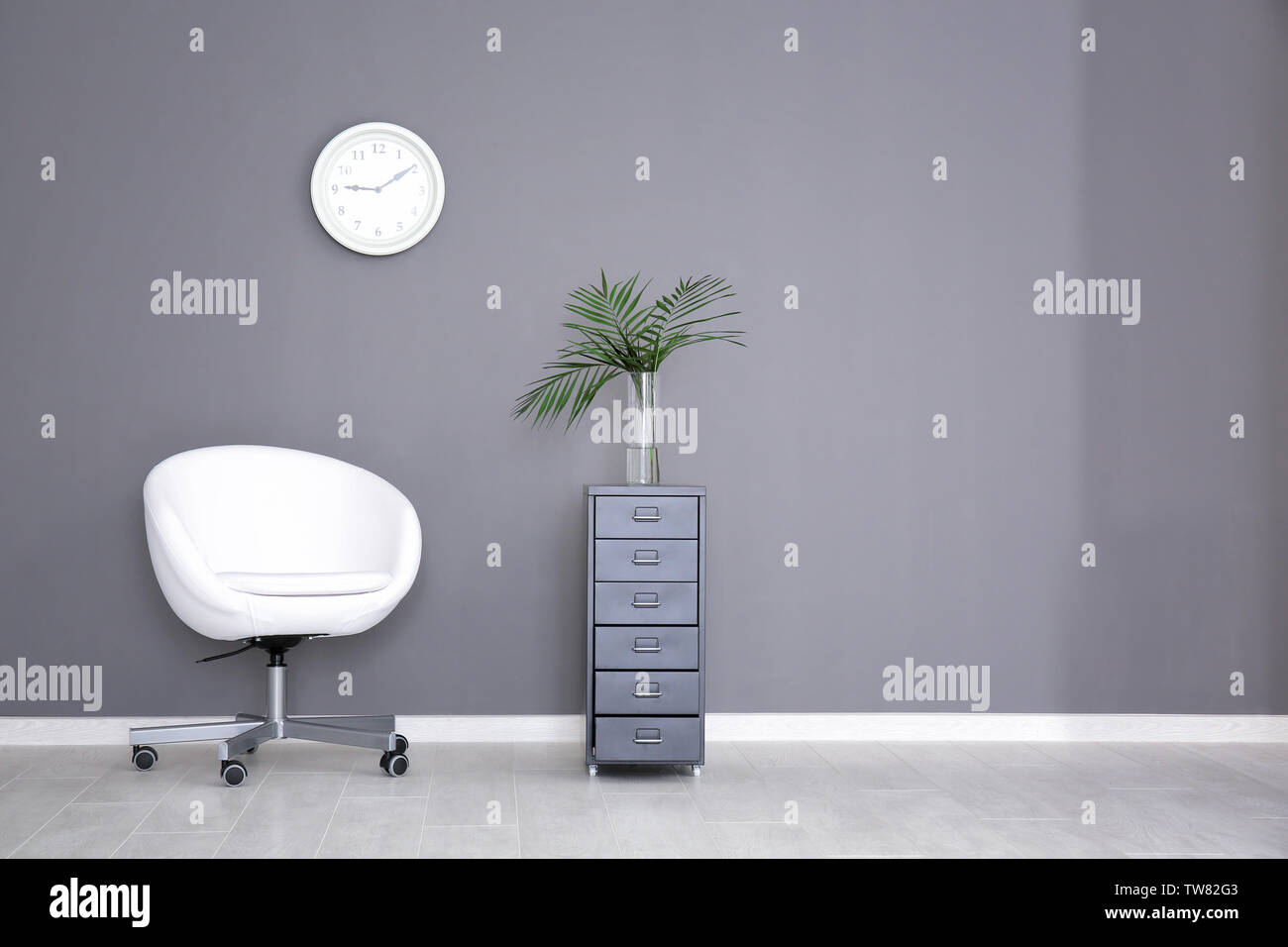 Minimalist interior with swivel chair and drawer unit Stock Photo - Alamy