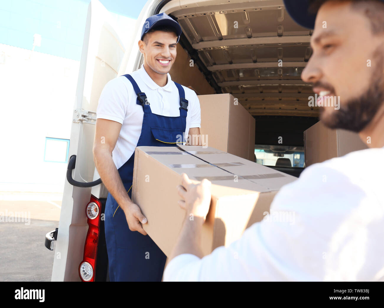 Delivery men unloading moving boxes from car Stock Photo