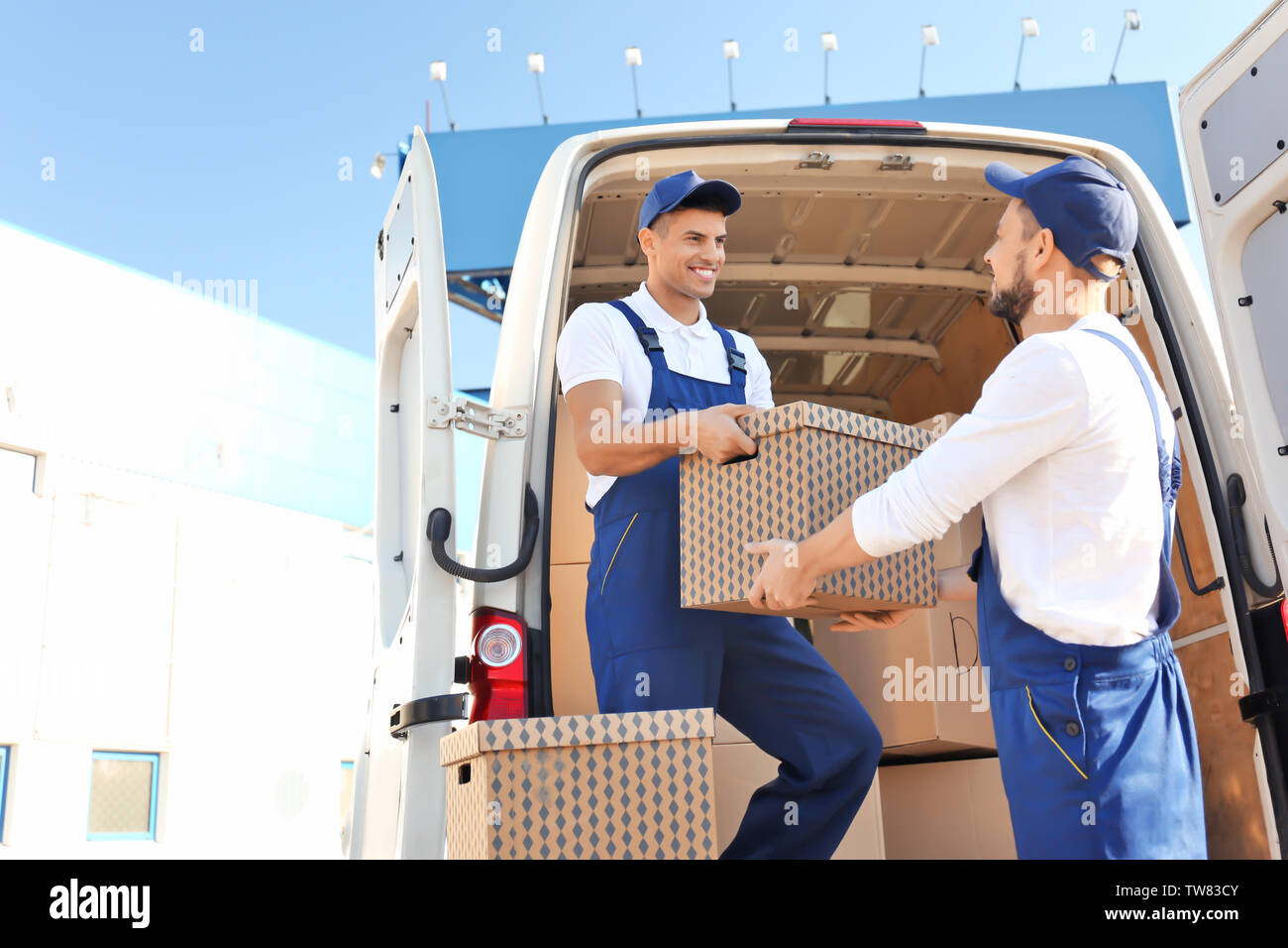 Delivery men unloading moving boxes from car Stock Photo