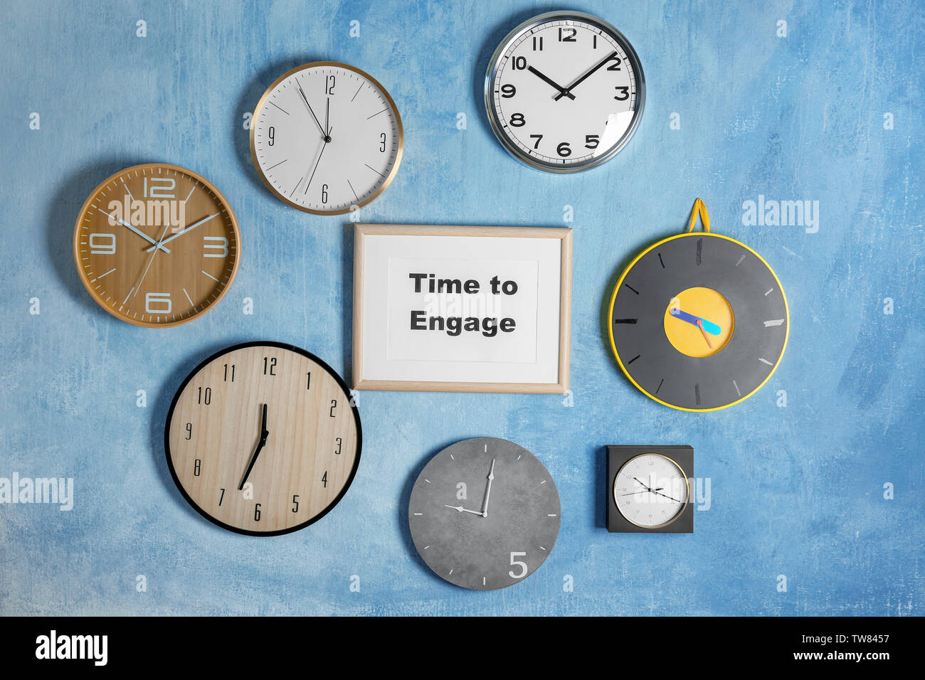 Clocks and frame with phrase TIME TO ENGAGE hanging on wall Stock Photo