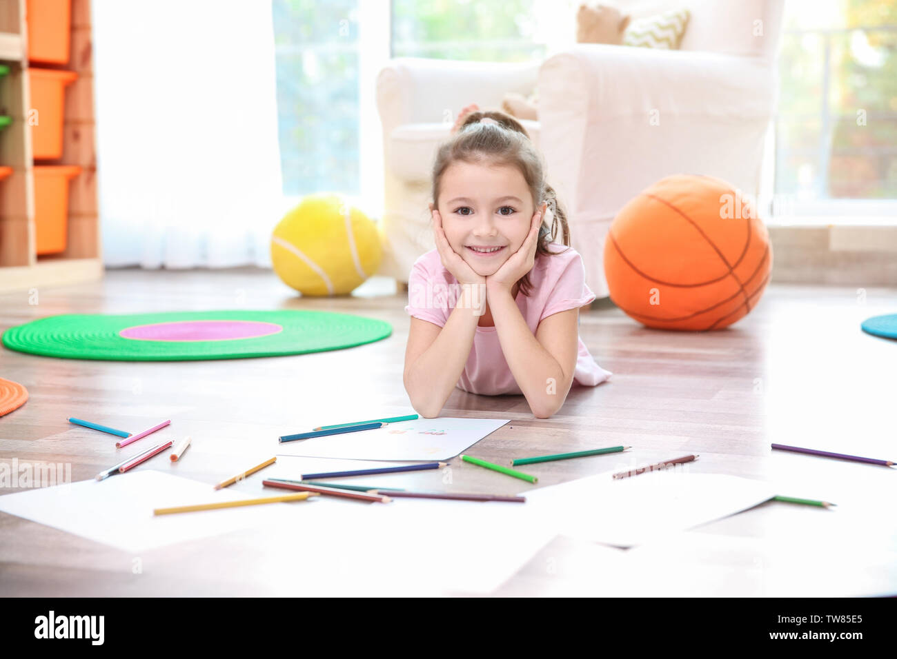 Little girl with color pencils and paper lying on floor at home Stock ...