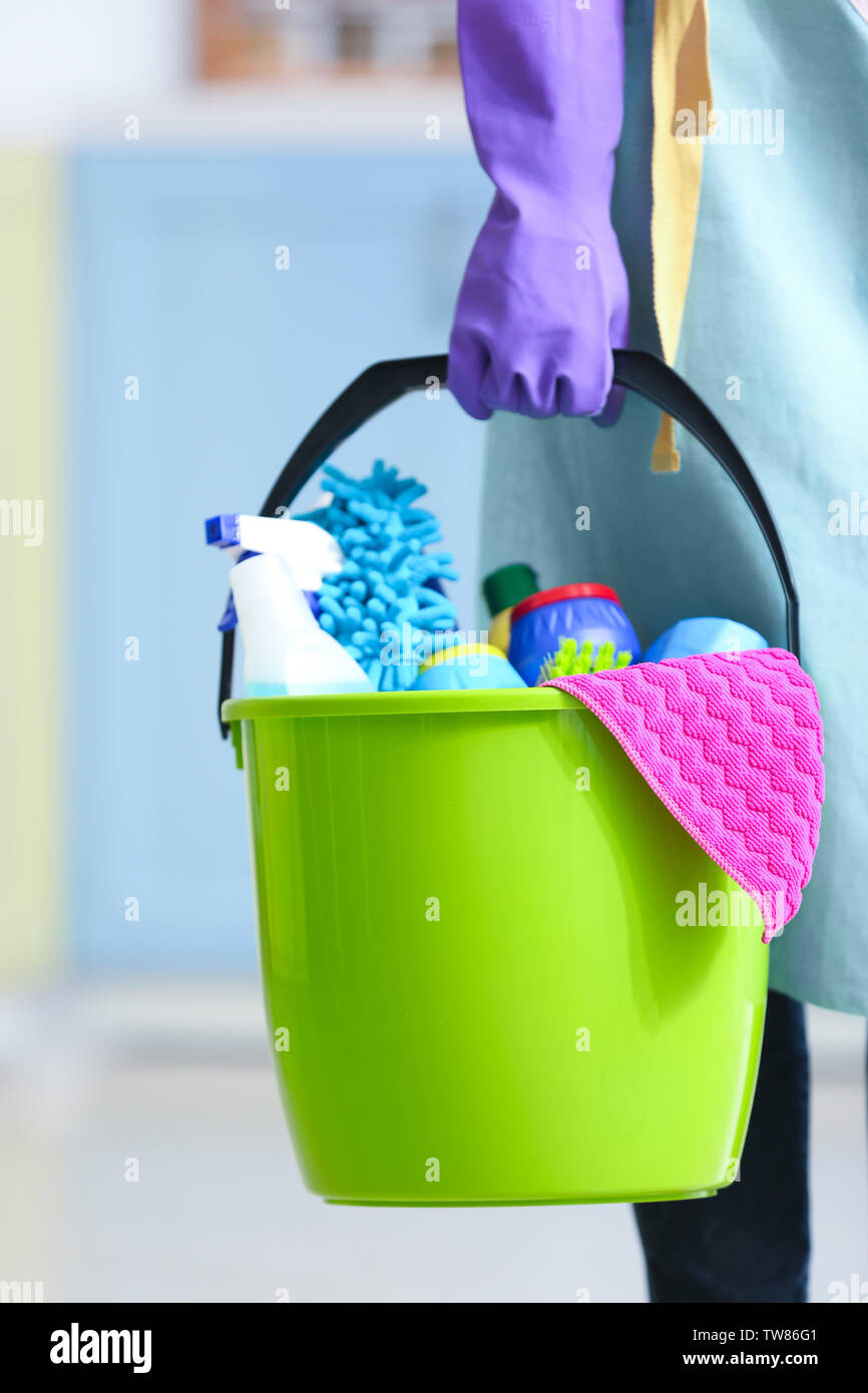 Woman holding bucket with cleaning products and tools indoors Stock ...