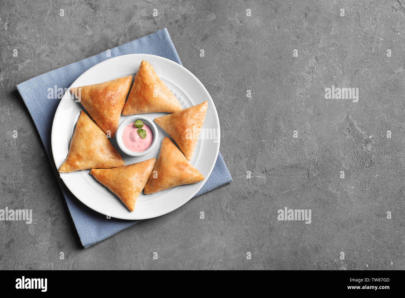 Plate with delicious samosas and sauce on grey background Stock Photo