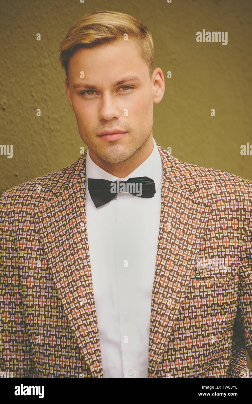 A Caucasian Male model, blonde, wearing a checker vintage sports jacket and black bow tie. He is handsome and confident. Stock Photo