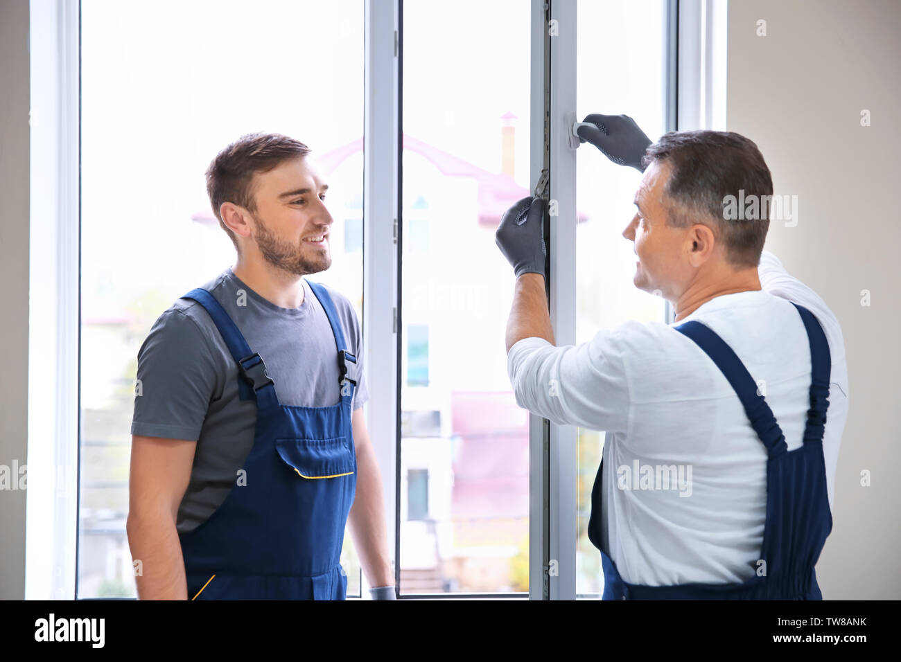 Construction worker with trainee installing window in house Stock Photo