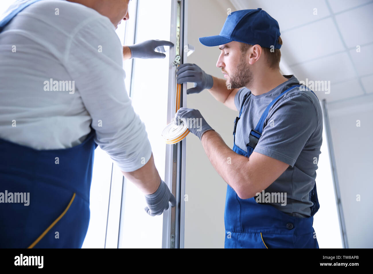 Construction worker with trainee installing window in house Stock Photo