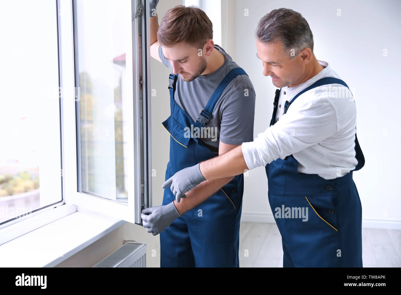 Construction worker with trainee installing window in house Stock Photo