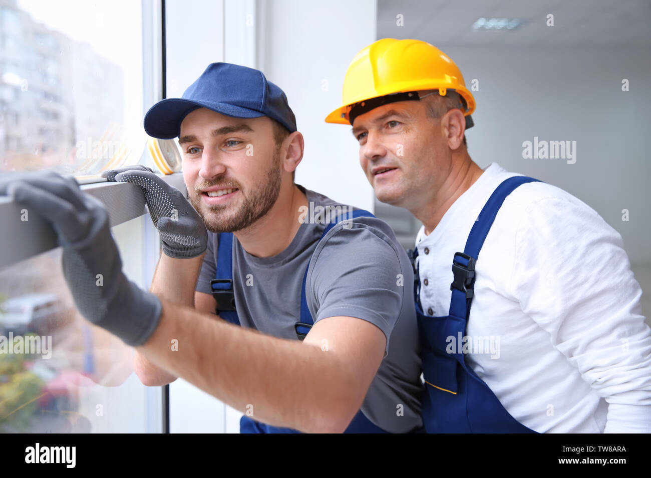 Construction worker with trainee installing window in house Stock Photo