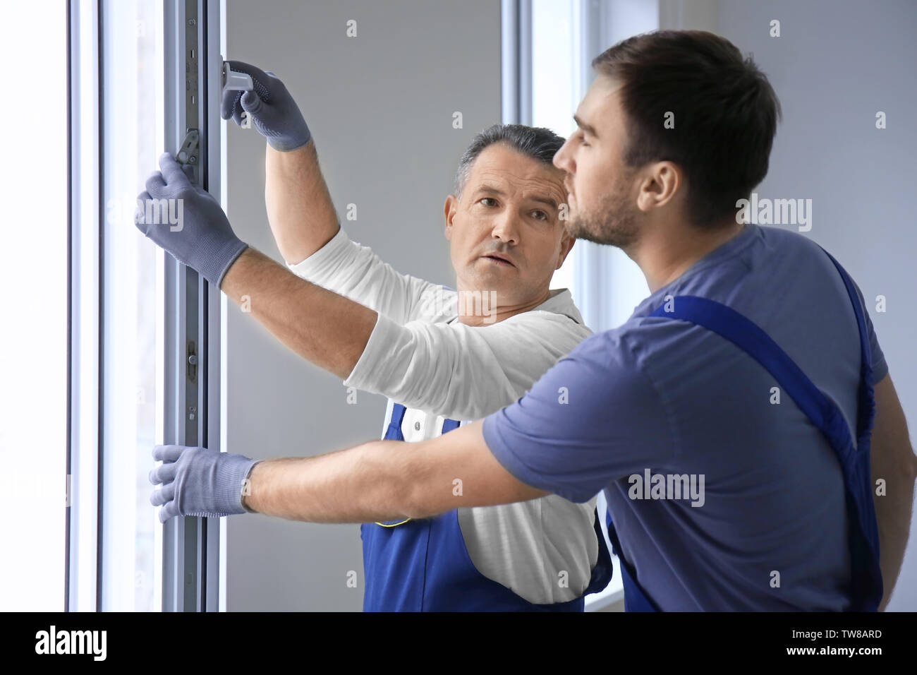 Construction worker with trainee installing window in house Stock Photo