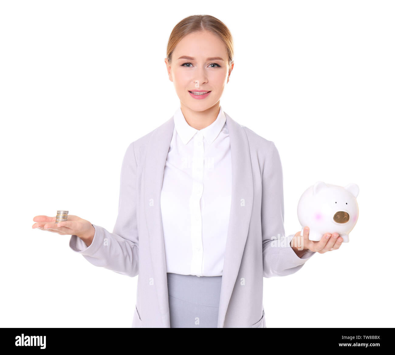 Young woman in formal clothes holding piggy bank and coins on white ...