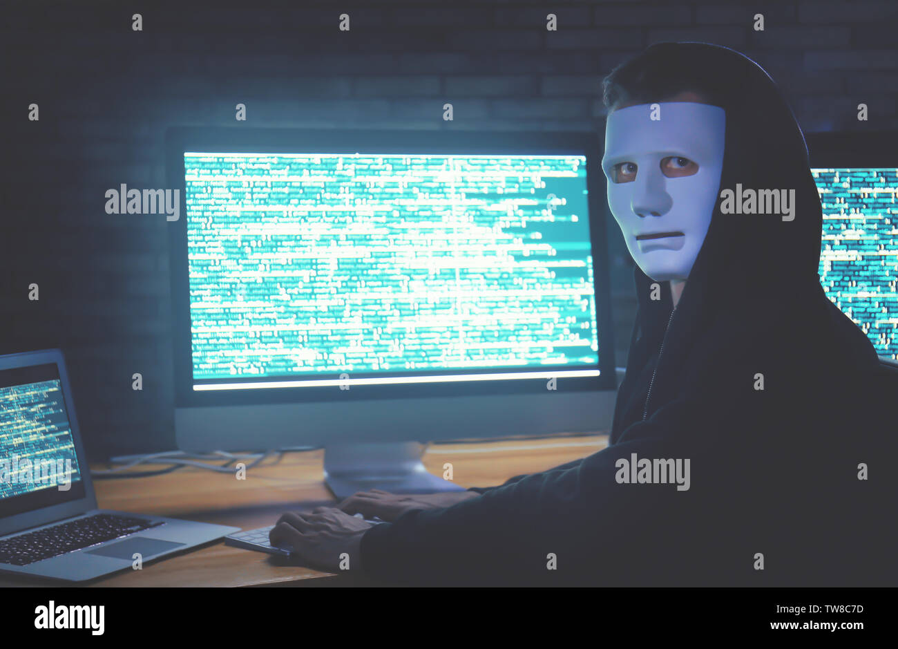 Masked hacker using computer in dark room. Threat of cyber attack Stock ...