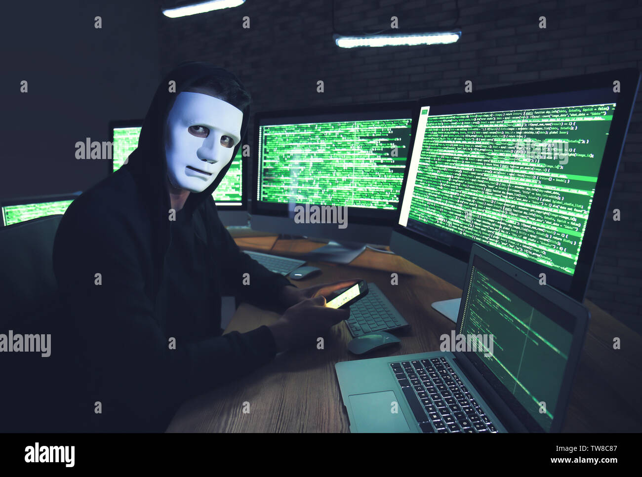Masked hacker using computer in dark room. Threat of cyber attack Stock ...