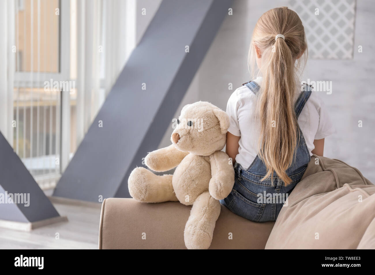 Lonely little girl with teddy bear in room. Autism concept Stock Photo ...