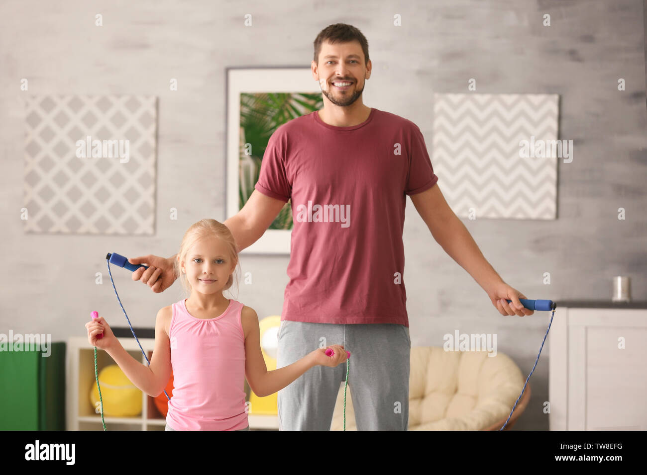 Cute girl and her father jumping rope at home Stock Photo - Alamy