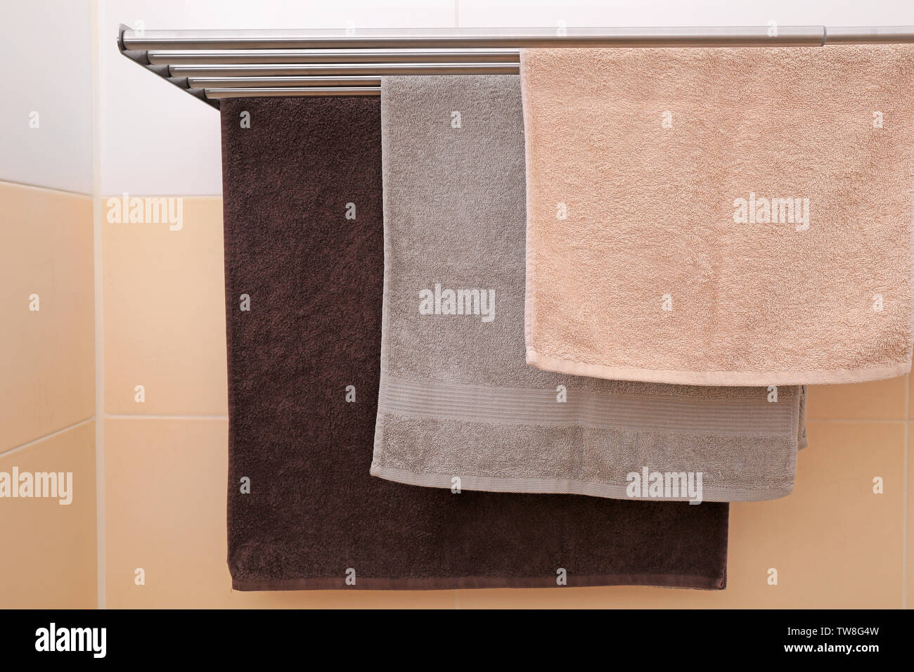 Soft towels drying on rack in bathroom Stock Photo