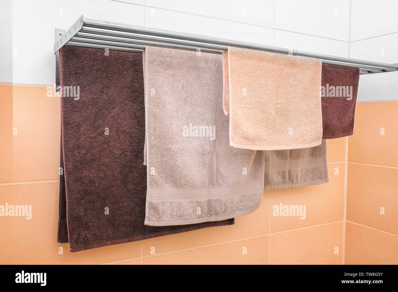 Soft towels drying on rack in bathroom Stock Photo
