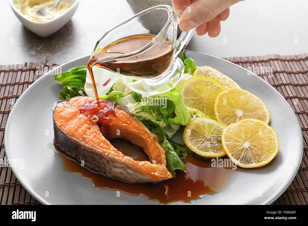 Pouring sauce onto tasty rainbow trout steak on plate Stock Photo Alamy