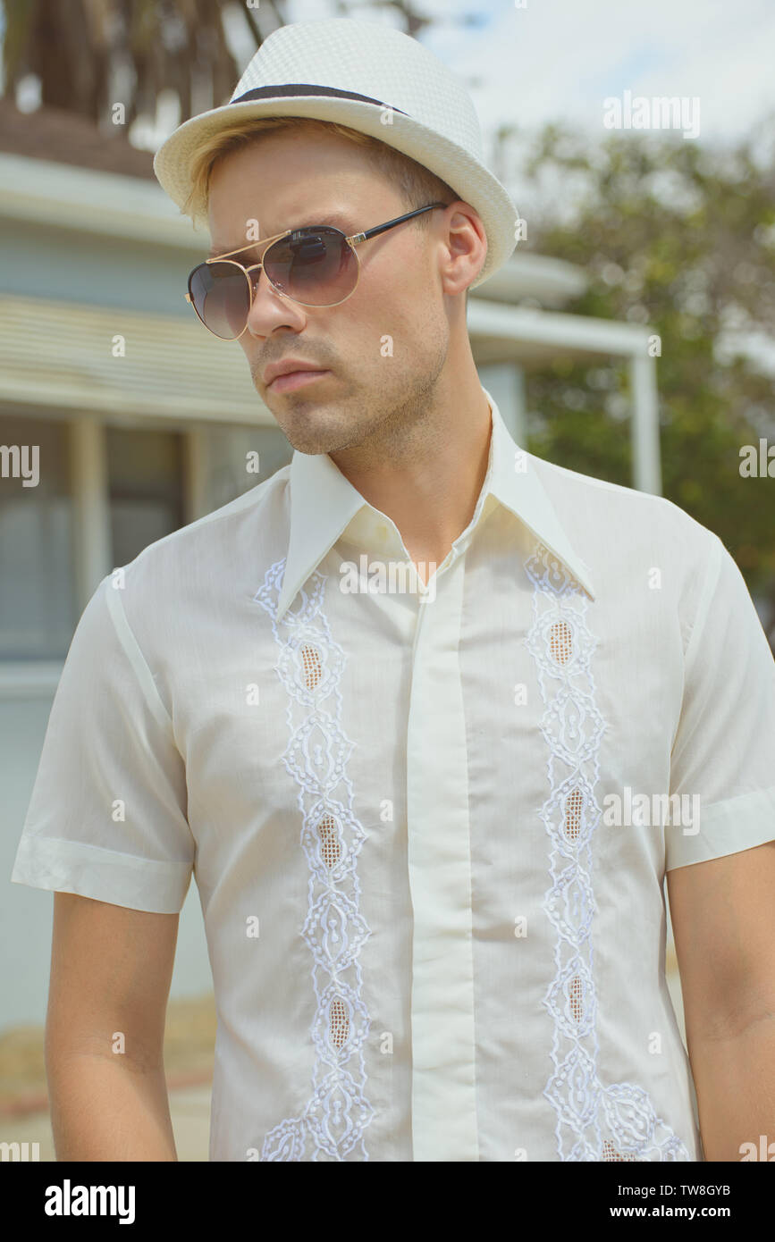 A handsome blond hair male model wearing a white 1970s  vintage shirt, posing outdoor. A male outdoor fashion portrait. Stock Photo