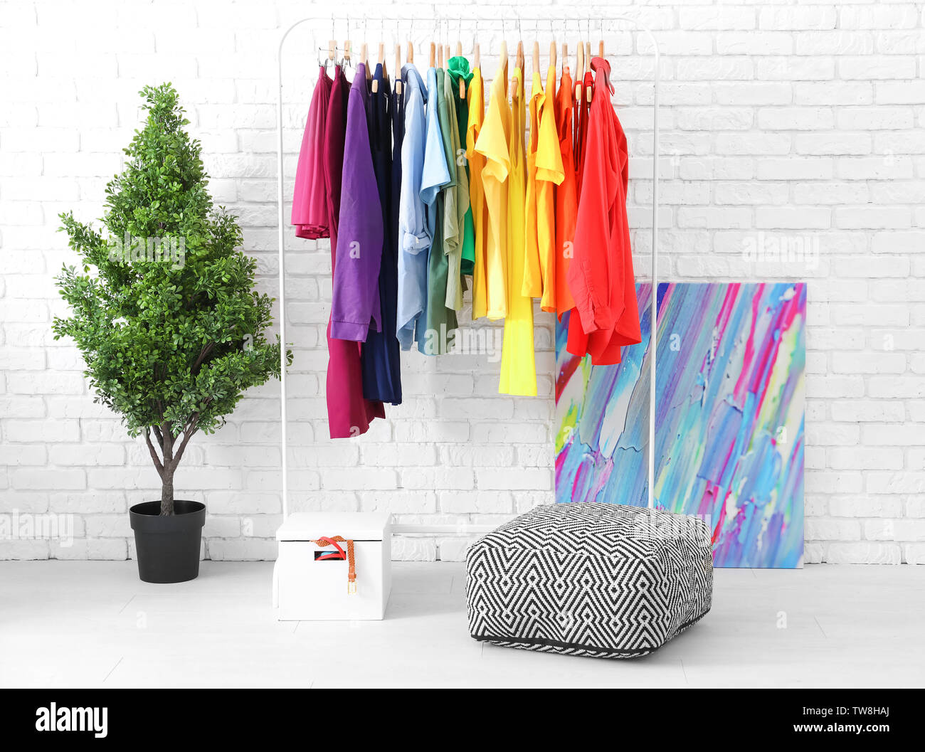Rack with rainbow clothes near brick wall Stock Photo - Alamy