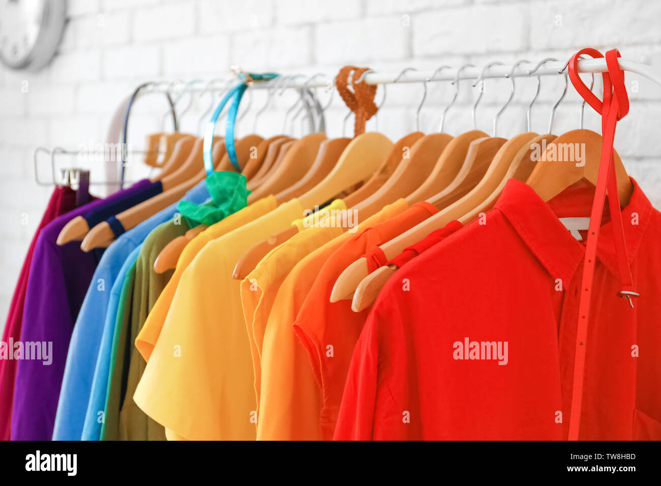 Rack with rainbow clothes near brick wall Stock Photo - Alamy
