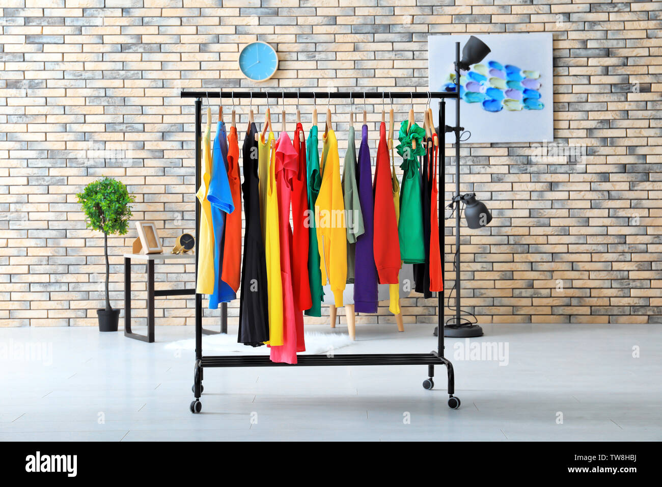 Rack with rainbow clothes near brick wall Stock Photo - Alamy