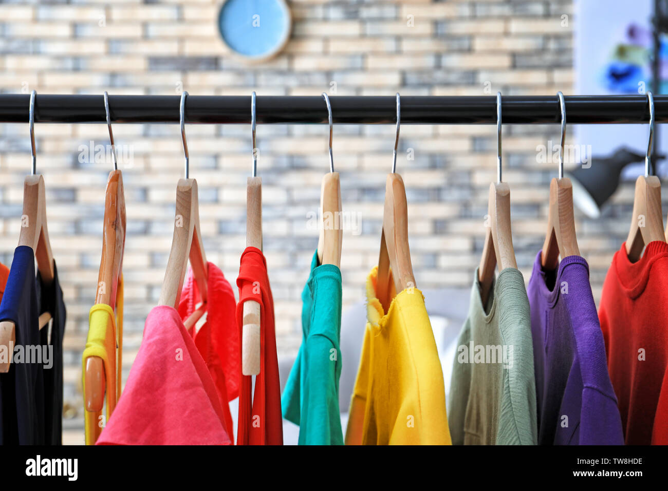 Rack with rainbow clothes indoors Stock Photo - Alamy