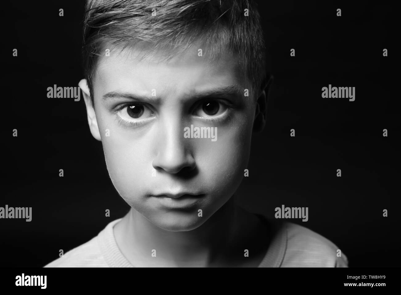 Upset little boy on dark background, black and white effect Stock Photo