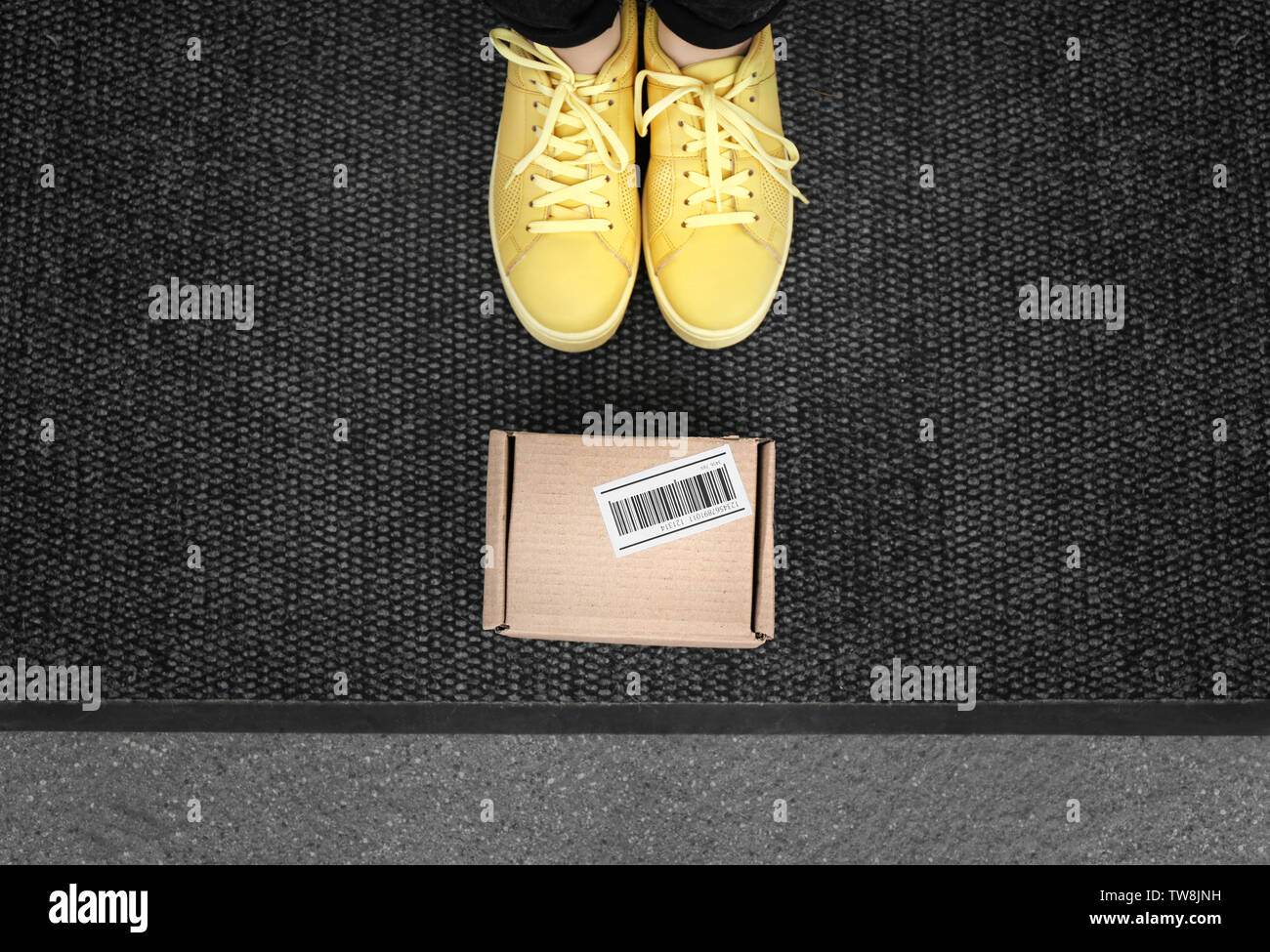 Woman standing near delivered parcel on doormat, closeup Stock Photo
