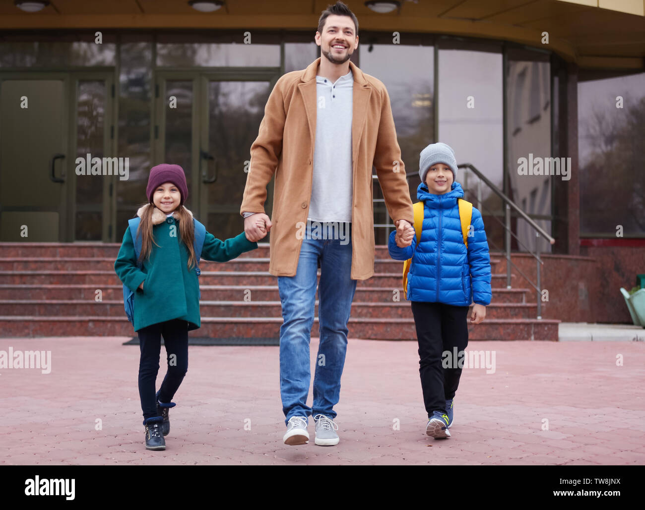 Young man walking his son and daughter to school Stock Photo