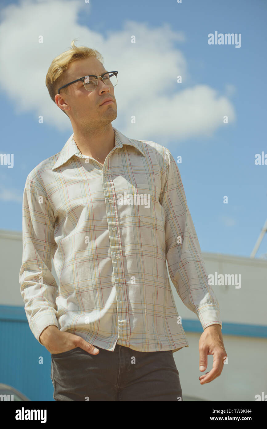 A handsome blonde male model wearing a vintage shirt posing outdoors, a men's vintage fashion concept. Stock Photo