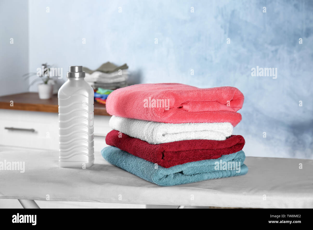 Folded towels and laundry detergent on ironing board Stock Photo Alamy