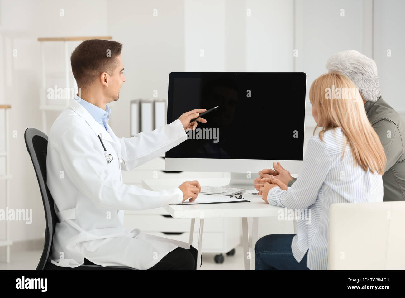 Male Doctor Consulting Senior Couple In Clinic Stock Photo