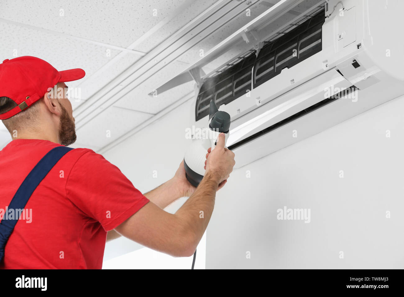 Male technician cleaning air conditioner indoors Stock Photo