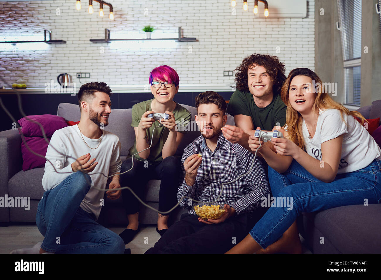 A group of friends playing video games in the room. Stock Photo