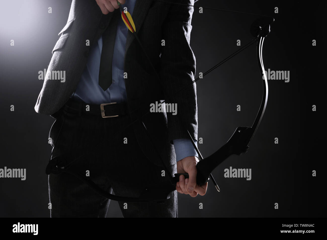 Businessman practicing archery on dark background Stock Photo