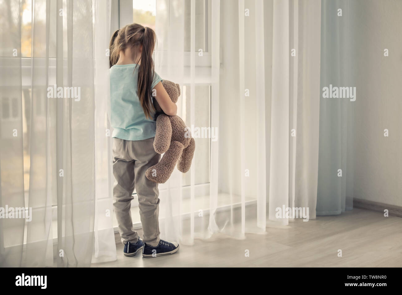 Lonely little girl with teddy bear near window. Autism concept Stock ...