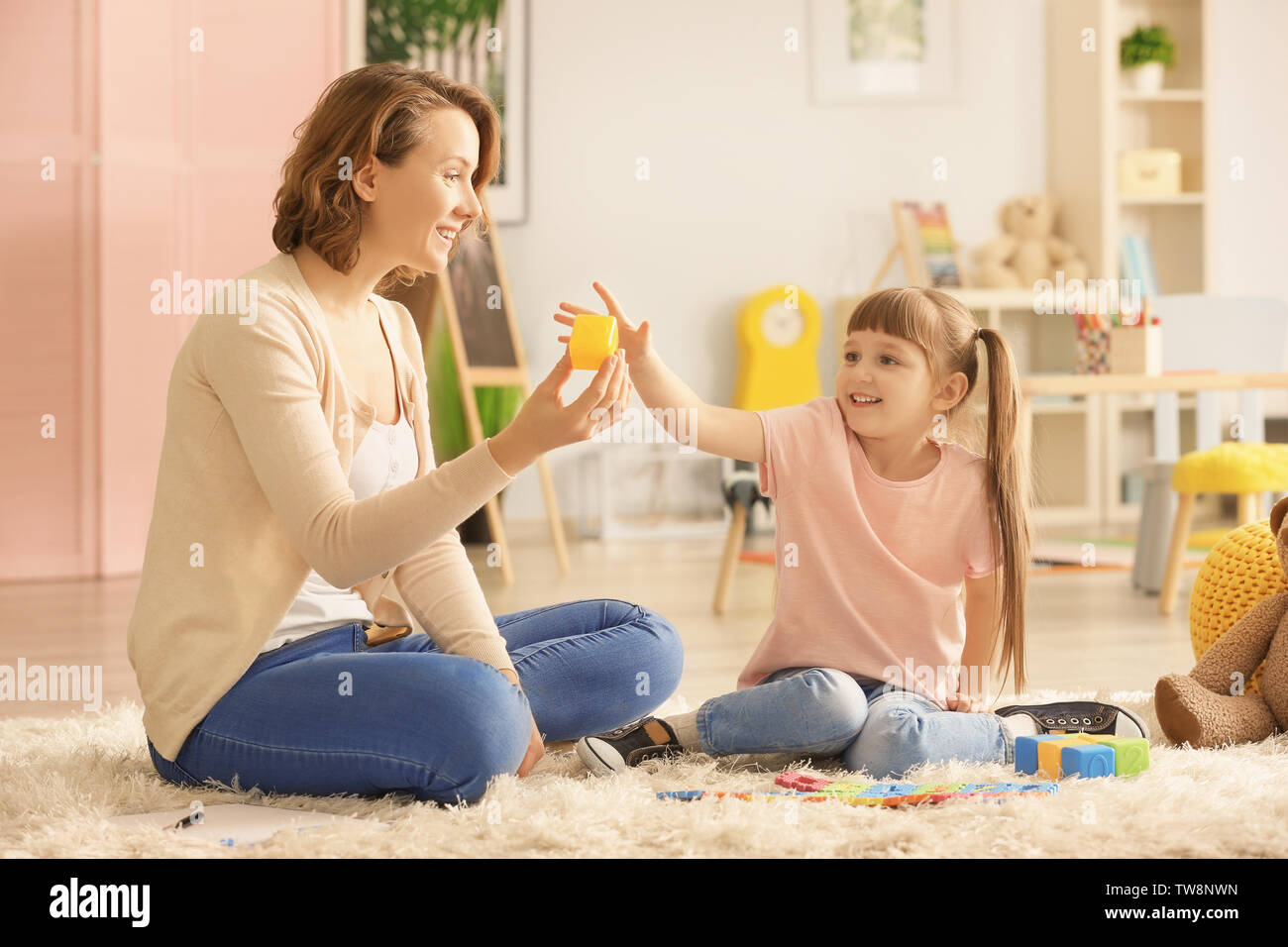 Female psychologist with cute little girl during play therapy Stock