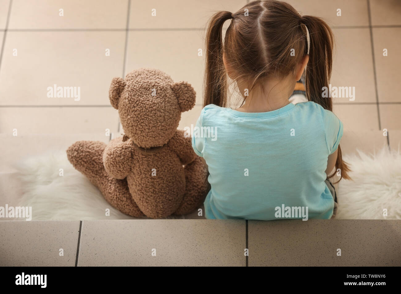 Lonely little girl with teddy bear sitting on stairs. Autism concept ...