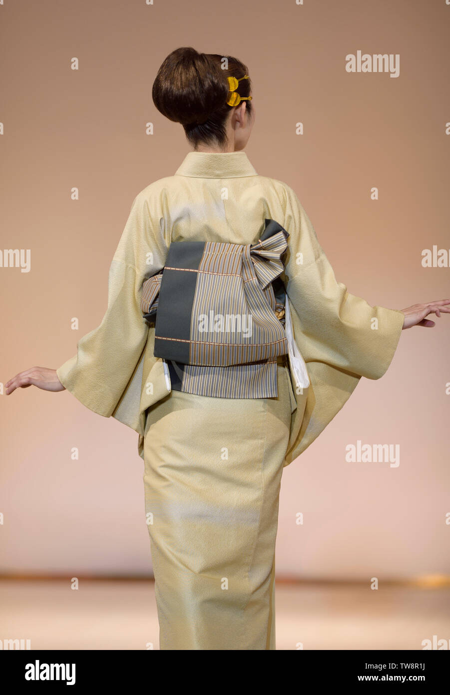 Back of a Japanese woman wearing an elegant light green yellow kimono with obi at a fashion show in Kyoto, Japan. Stock Photo