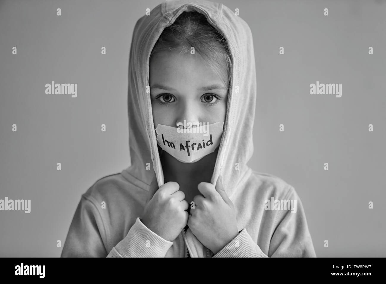 Sad little girl with taped mouth and words 