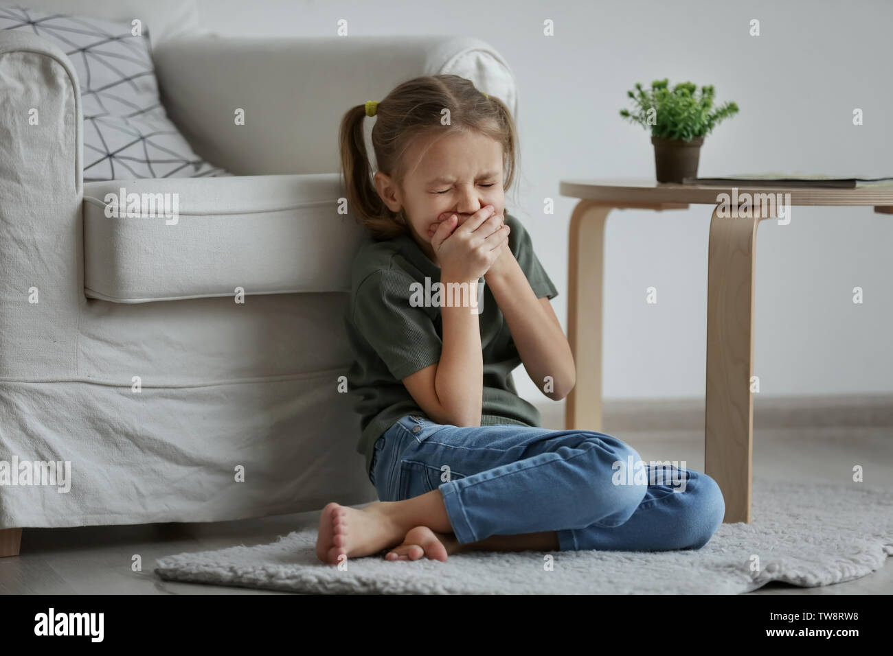 Sad little girl sitting on floor indoors Stock Photo - Alamy